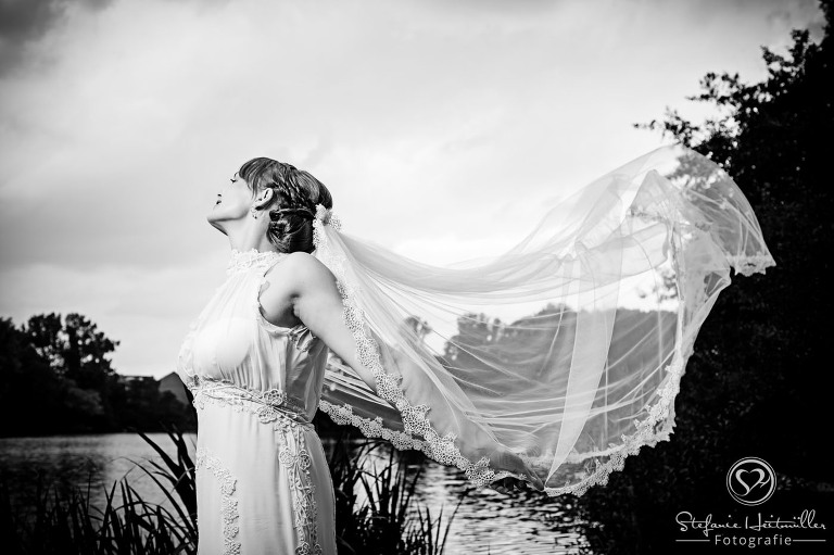 Ein langer Schleier einer Braut schwebt bei Hochzeitsfotos im Wind.